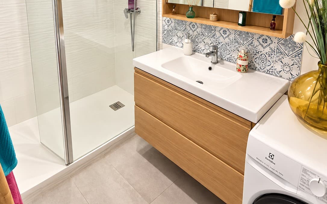 Salle de bain d’un client, douche vitrée, meuble vasque en bois et crédence en carreaux bleus et blancs