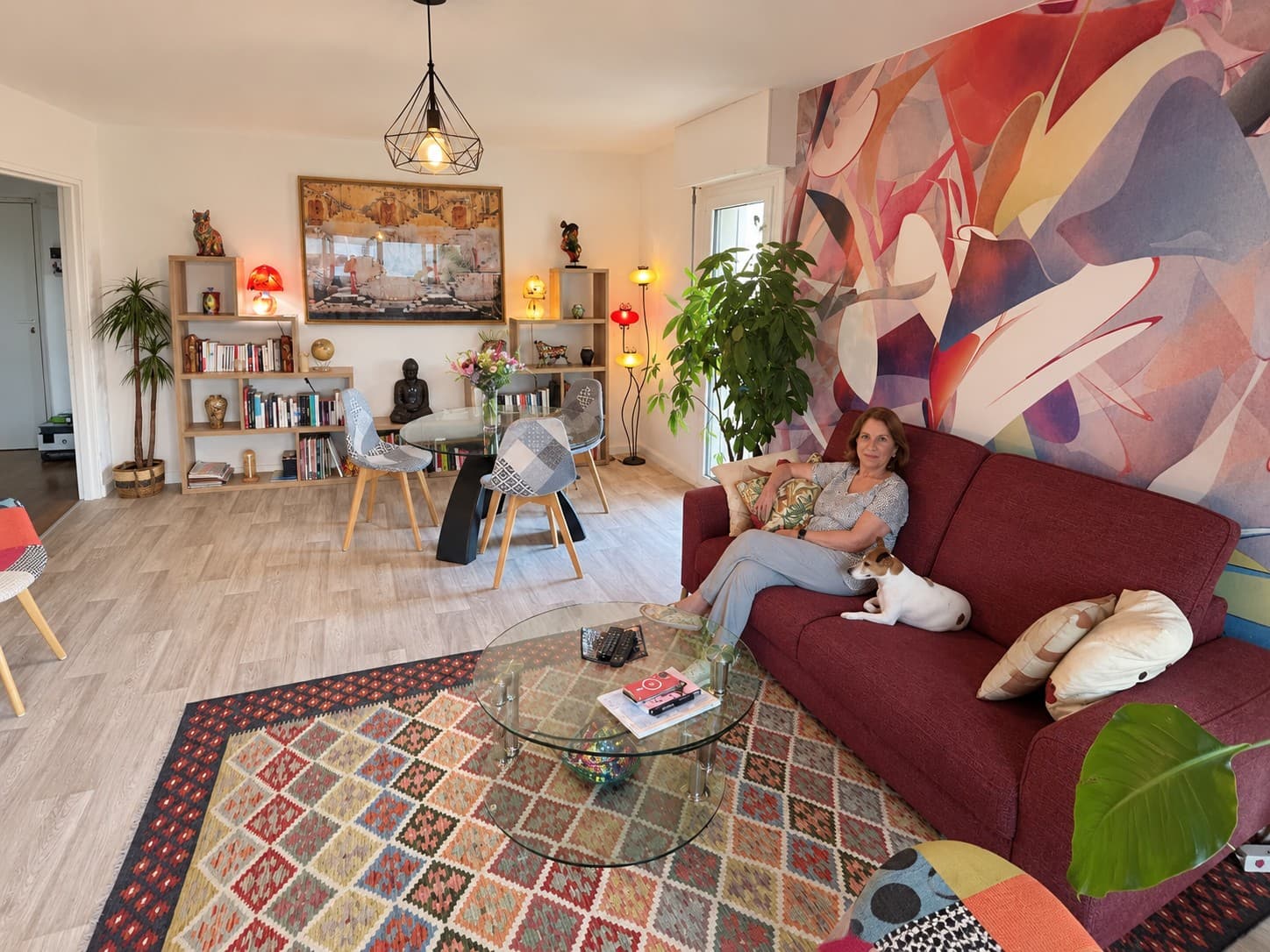 Salon d’une cliente, tapis coloré et canapé bordeaux où elle s’est installée avec son chien