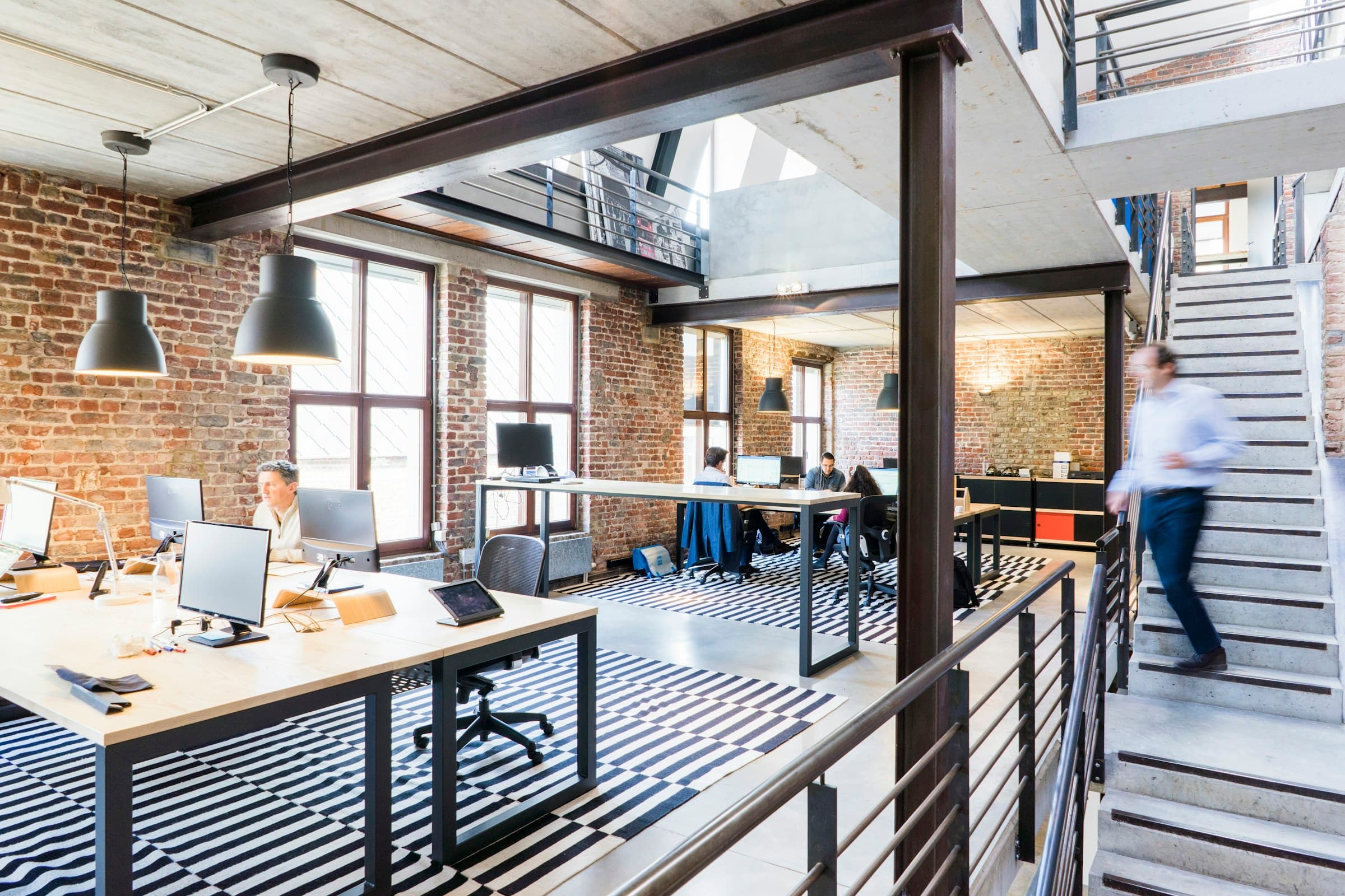 Bureaux en open space dans un loft en briques, postes de travail et mezzanine